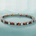 Détail macro du bracelet tennis argenté avec pierres ovales rouges et claires sur tissu - Style Zircone Blanc/Rouge Rond et Ovale Argenté (B0093-1)