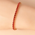 Detailed close-up of a gold-plated tennis bracelet with round-cut red crystals on wrist - 16.5+5cm / Red