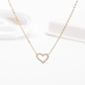 Dettaglio del ciondolo a cuore dorato con zirconi incastonati su una catena sottile - Stile Cuore Cavo / Oro