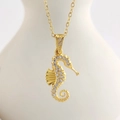 Detailed view of a golden seahorse pendant necklace with white crystals on a white bust - Gold Seahorse (N0406G)