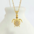 Detail view of a gold turtle pendant necklace with sparkling cubic zirconia on a white bottle - Gold Sea Turtle (N0408G)