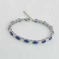 Detail van zilveren tennisarmband met ovale blauwe en heldere zirkonia-stenen - Zilver + Witte & Koningsblauwe Steen