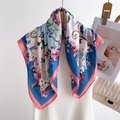 Floral print silk scarf in sky blue and ivory hung elegantly on a wooden hanger - Pink Border (FG2-2)