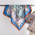 Detail of floral silk scarf with blue border and orange rolled hem next to a handbag - Red Border (FG2-1)