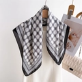 Elegant geometric silk square scarf with H pattern draped on a hanger with a luxury handbag - Black