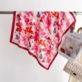Dettaglio della sciarpa in seta a fiori rossi drappeggiata su un'asta con borsa a catena - Rosso
