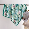 Dettaglio di un elegante foulard in seta a fiori verdi con texture di tessuto morbido - Verde