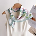Dettaglio di un foulard in seta floreale su un abito bianco con eleganti stampe rosa e verdi - Verde