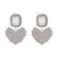 Dettaglio macro di orecchini a cuore pixel argento con pavé di strass scintillanti - Bianco