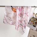 Dettaglio di un foulard in raso leggero con stampa floreale e uccelli e bordi arrotolati - Rosa