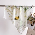 Dettaglio di un foulard in seta con stampa floreale e uccelli appeso con eleganza - Verde