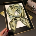 Olive green paisley silk scarf with geometric patterns displayed in a luxury setting - 147x14cm / Green