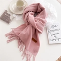Detail view of light pink fringe scarf with leather brand label and cozy winter accessories - Pink