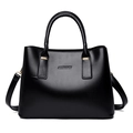Detalle del bolso trapezoidal negro mostrando el cuero brillante y herrajes dorados - Negro