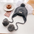 Close-up of dark grey knitted Balaclava with fluffy pom-poms and minimalist logo tag - Dark Gray