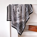 Dettaglio macro di un foulard in seta con motivi paisley e barocchi su uno scaffale - 90x90cm / Nero