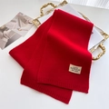 Nahaufnahme eines roten Strickschals mit Etikett auf einem goldenen Vintage-Tablett - Burgunderrot