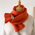 Détail de la texture d'une écharpe en maille orange avec étiquette vintage sur manteau - Orange