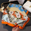 Detailaufnahme der seidigen Textur und des lebendigen Blumendrucks des Schals - 70x70cm / Orange