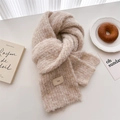 Detail of soft cream wool knit scarf texture with minimal woven label on white table - Beige