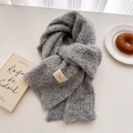 Detail of gray boucle wool scarf with ins label on white table with lifestyle props - Gray