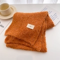 Close-up of bright orange textured wool scarf with minimalist ins woven label detail - Orange