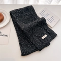 Close-up of thick charcoal grey cable knit wool scarf with a woven label on white table - Mixed Grey