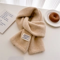 Detail shot of beige wool knitted scarf with a textile label on a clean aesthetic background - 156x24cm / Beige