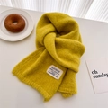 Detail of ginger yellow knitted mohair scarf with fabric tag on a cozy table setting - 156x24cm / Yellow-Green