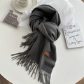 Dark gray tassel scarf with leather logo label in a cozy minimalist setup - Marl Grey