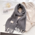 Detail of gray chunky knit wool scarf with tassel fringe and minimalist brand label - Gray