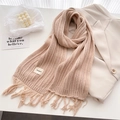 Detail shot of chunky knit texture and fringe tassels on a beige wool winter shawl - Khaki