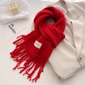 Detail of red cable knit wool scarf with fringe and brand label on a beige blazer - Red