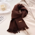 Detail of dark brown knitted scarf showing thick texture, fringe, and leather Hand Made label - Brown