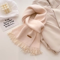 Detailed view of handmade leather label and fringe on a thick knit beige winter scarf - Beige