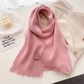 Detail view of pink knitted scarf featuring soft fringe edges and a leather handmade label - Light Pink