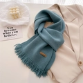 Detailed texture of Morandi blue knitted scarf with fringes and handmade leather tag - Denim Blue