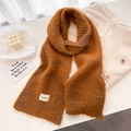 Détail d'une écharpe en laine tricotée orange chaud avec texture douce et étiquette - 161x21cm / Chameau