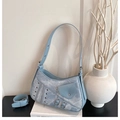 Detailed macro shot of light blue denim saddle bag texture with silver hardware and buckles - Blue