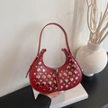 Sac hobo en cuir rouge avec clous argentés et double fermeture éclair sur un livre - Rouge