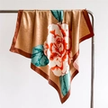 Dettaglio del foulard in raso champagne con petali di fiori arancioni e foglie verdi - Cachi