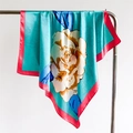 Detail of teal satin scarf with floral prints and red rolled hem on metal hanger - Sky Blue