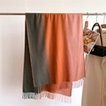 Nahaufnahme eines Strickschals mit Farbverlauf von Grün zu Orange und Fransen - Grün