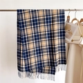 Detail of navy and beige plaid scarf with soft tassels hanging on a metal rack - Navy Blue