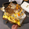 Vista dettagliata di un foulard in seta con motivi floreali gialli e marroni su display - Marrone