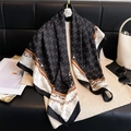 Detailed close-up of a luxury silk scarf featuring elegant chain motifs and letter patterns - Black