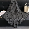 Detailed view of luxury geometric silk scarf draped on a black leather sofa surface - Black / 90x90cm
