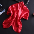 Detail of red satin scarf edge stitching and silk texture draped on black background - Red