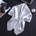 Gros plan d'un foulard en satin gris argenté suspendu à un cintre en bois chic - Gris Argent