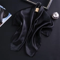Vue détaillée d'un foulard en satin noir brillant sur un cintre en bois au décor chic - Noir